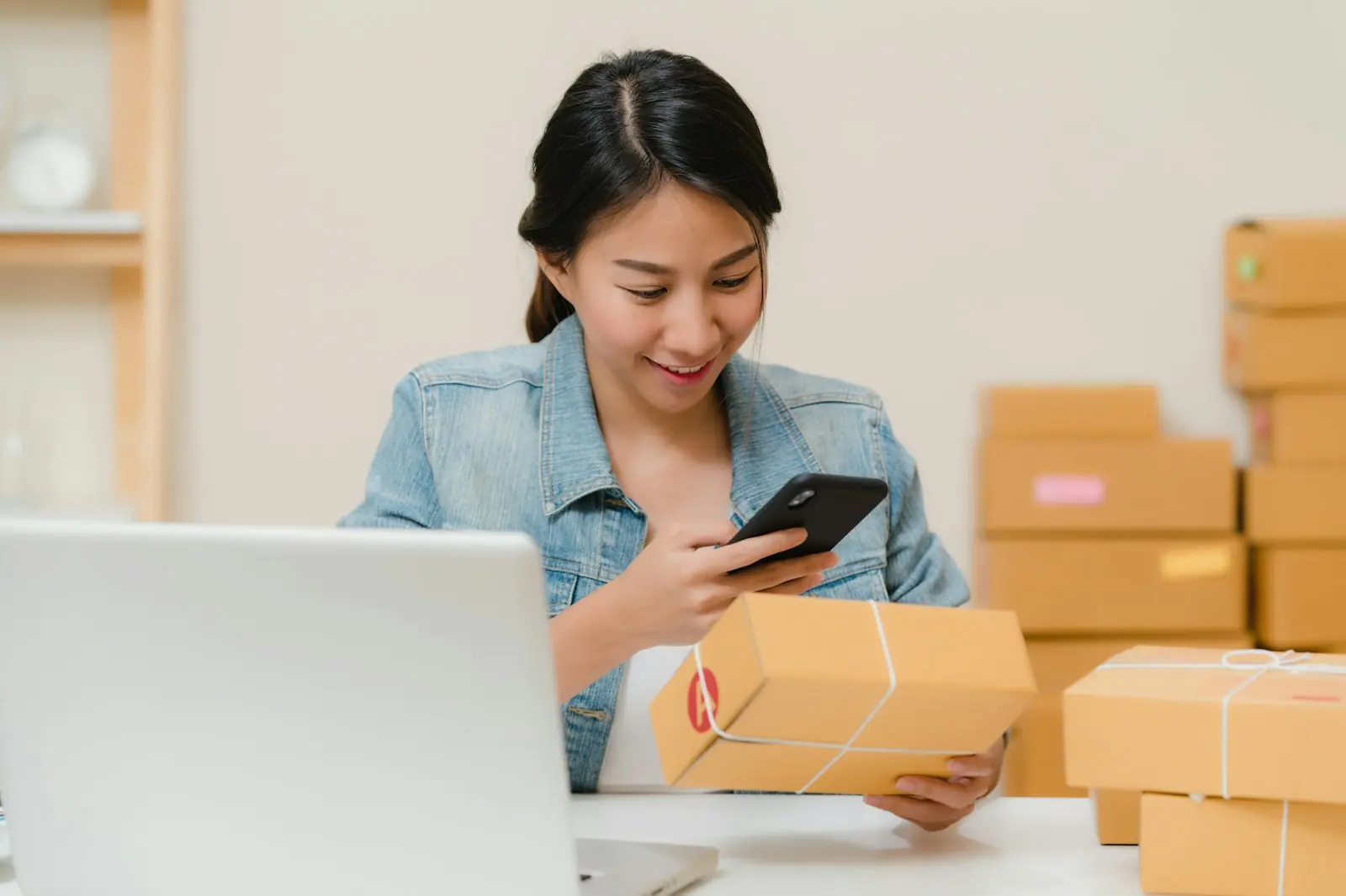 Online shop owner packing an order next to her laptop